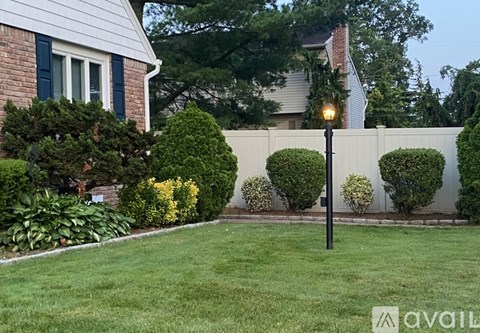 A well-maintained lawn in front of a house with a white fence.