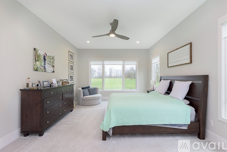 A bedroom with a bed, dresser, and ceiling fan.