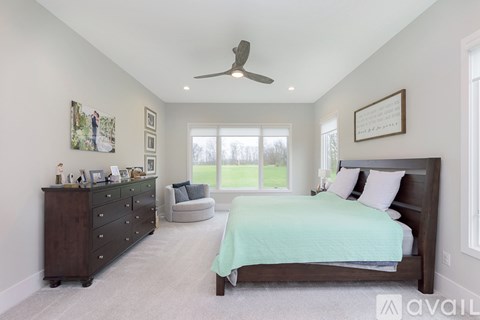 A bedroom with a bed, dresser, and ceiling fan.