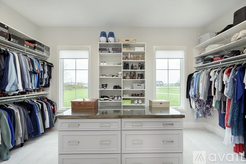 A spacious walk-in closet with white shelves and drawers.