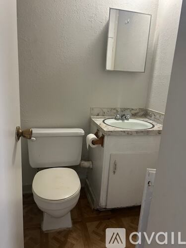 A white toilet with a toilet paper holder and a white sink with a mirror above it.