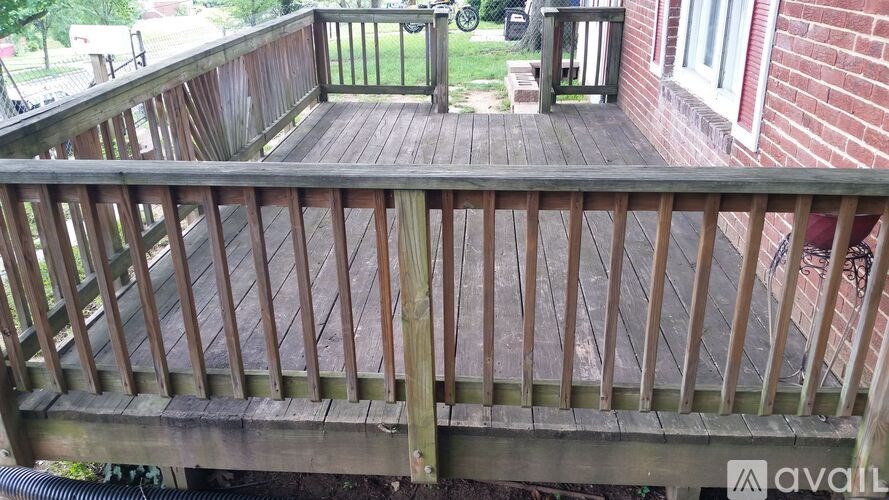A wooden deck with a railing and a hose underneath.