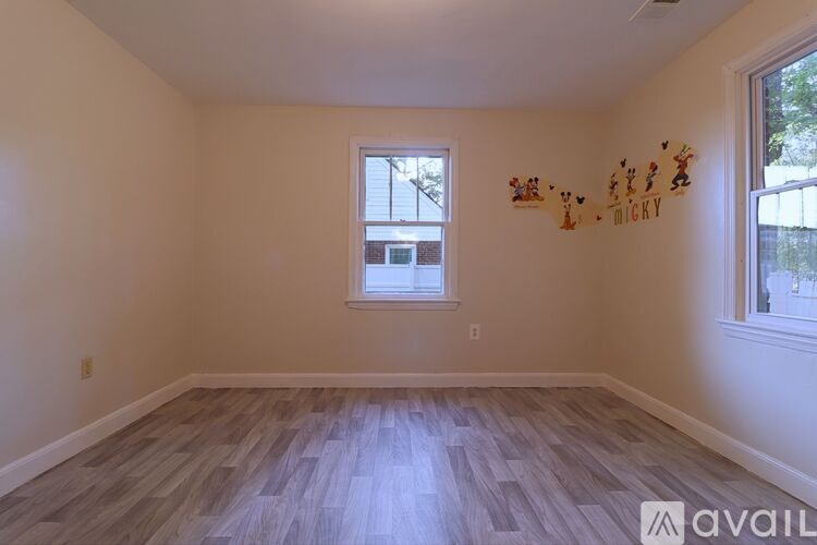 A room with wooden flooring and a window with a view of a building outside.