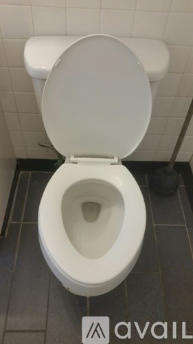 A white toilet with the lid up in a tiled bathroom.