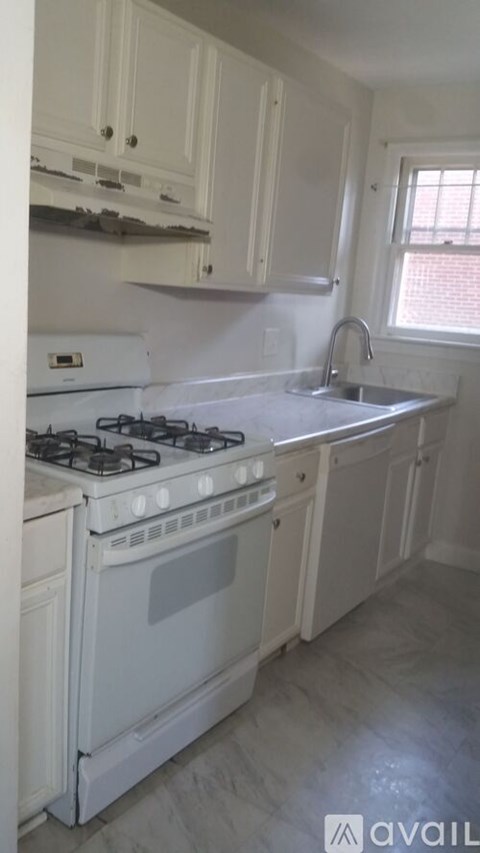 A white gas stove in a kitchen with white cabinets.