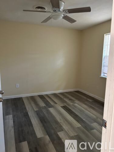 A room with a ceiling fan and wooden flooring.