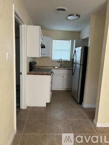 A kitchen with white cabinets and appliances, a sink, and a window.