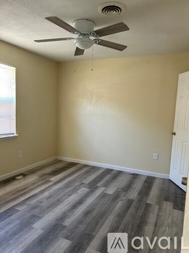 A room with a ceiling fan and wooden flooring.