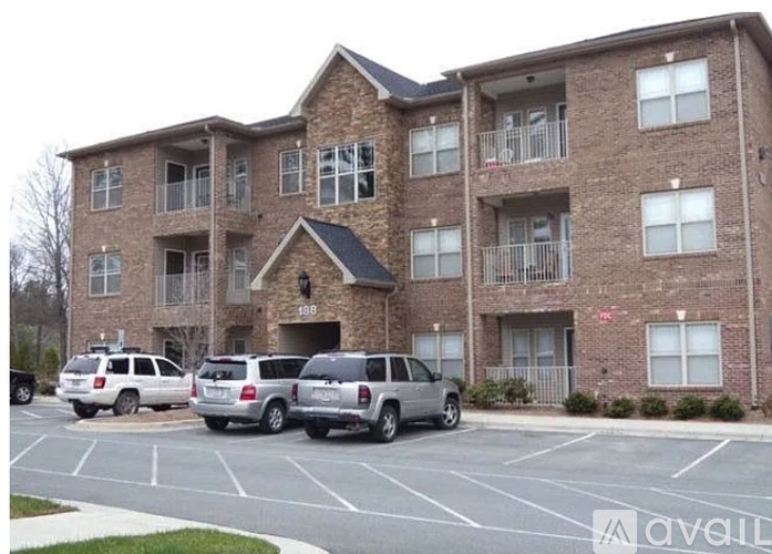 A brick apartment building with three cars parked in front.