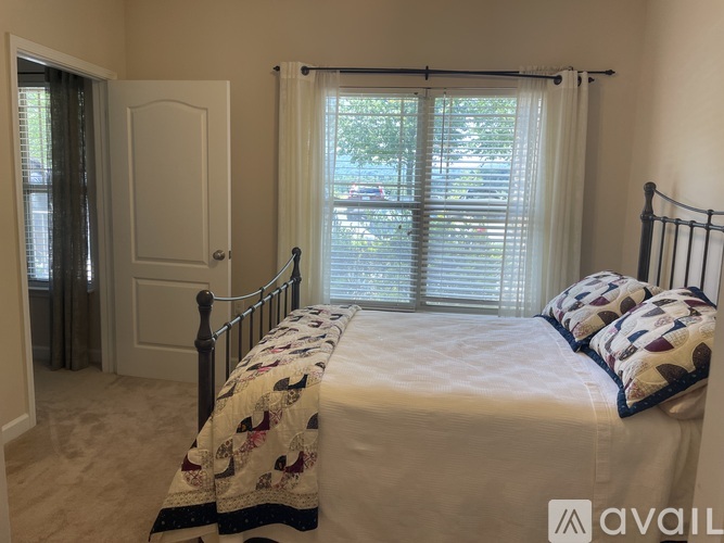 A bedroom with a bed, pillows, and a window with blinds.