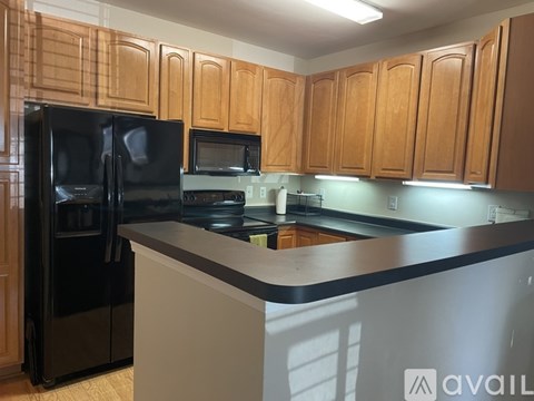 A kitchen with wooden cabinets and black appliances.