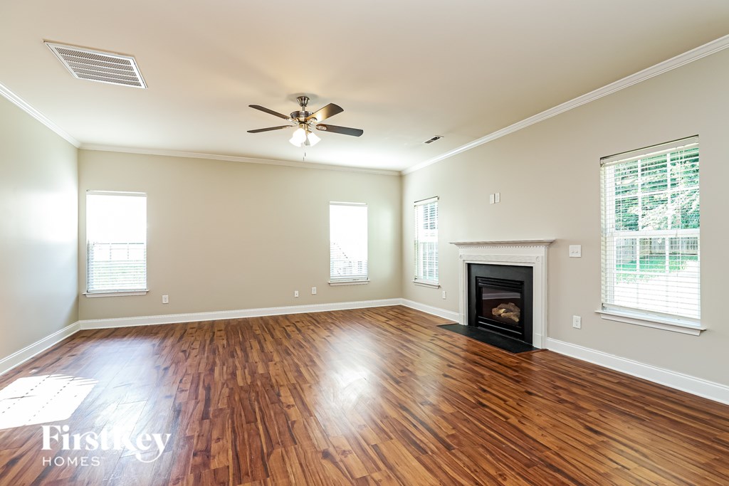 A spacious room with a fireplace and wooden flooring.
