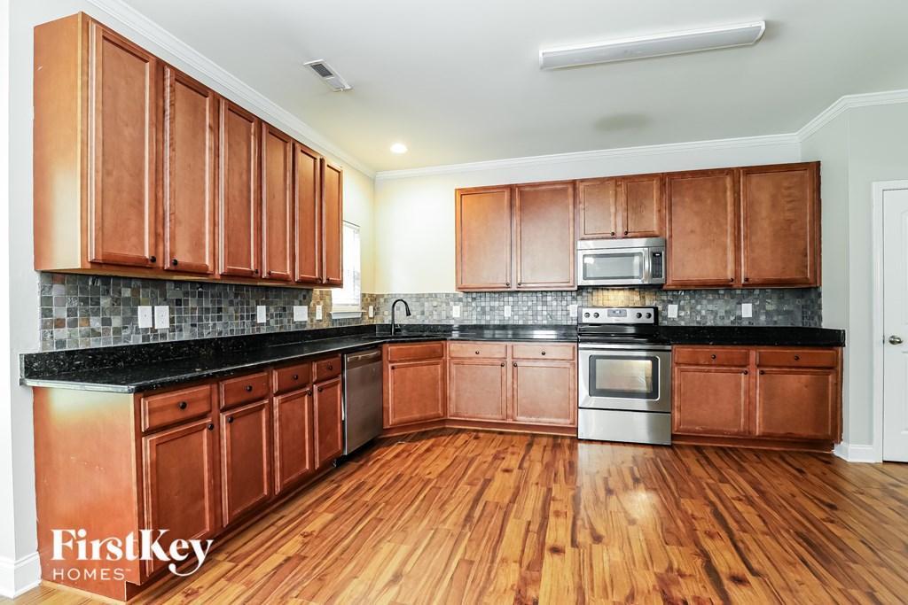 A kitchen with wooden cabinets and a black counter top.