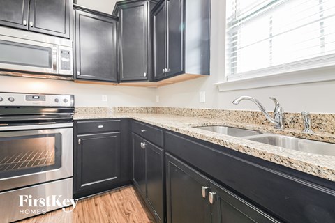 A kitchen with black cabinets and a stove top oven.