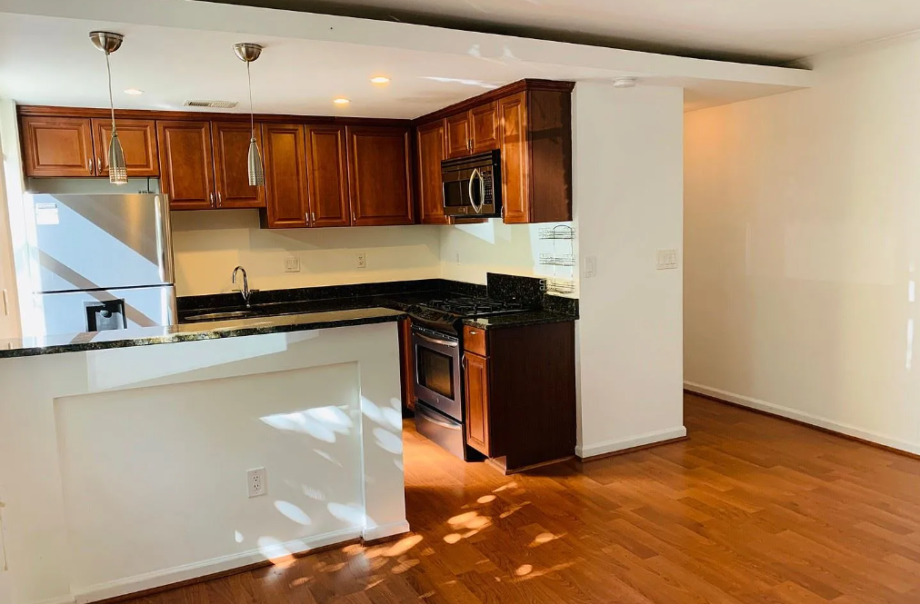 A kitchen with brown cabinets and black countertops.