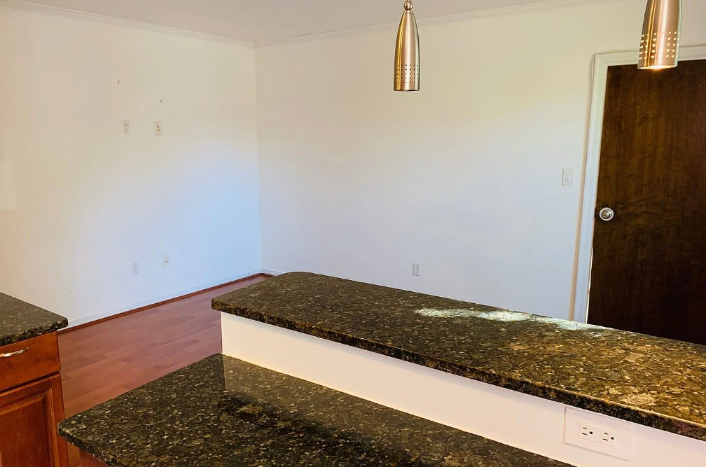 A kitchen counter with a granite top and white base.