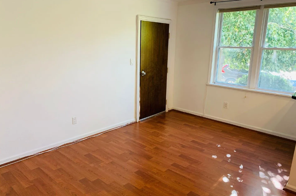 A room with a wooden floor and a door leading to a balcony.