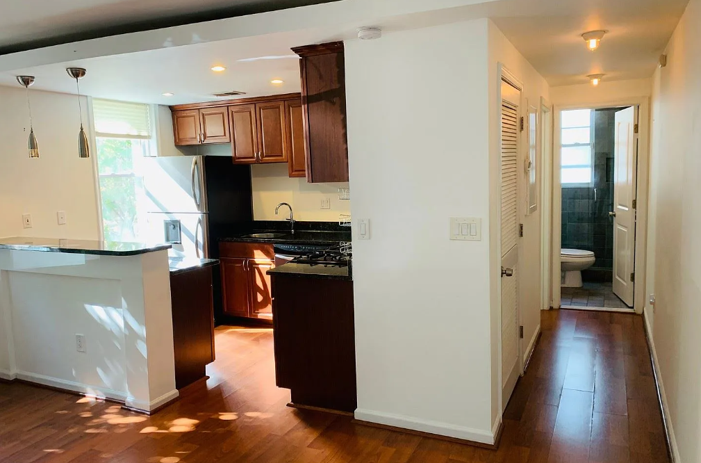 A kitchen with dark wood floors and white walls.
