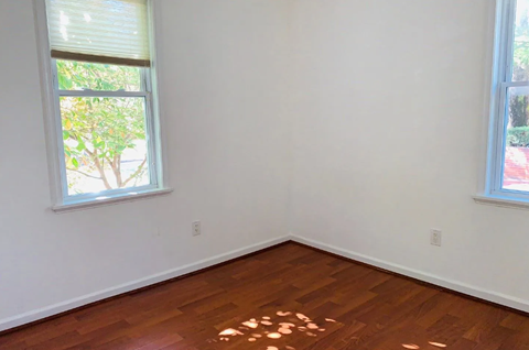 A room with a window and a wooden floor.