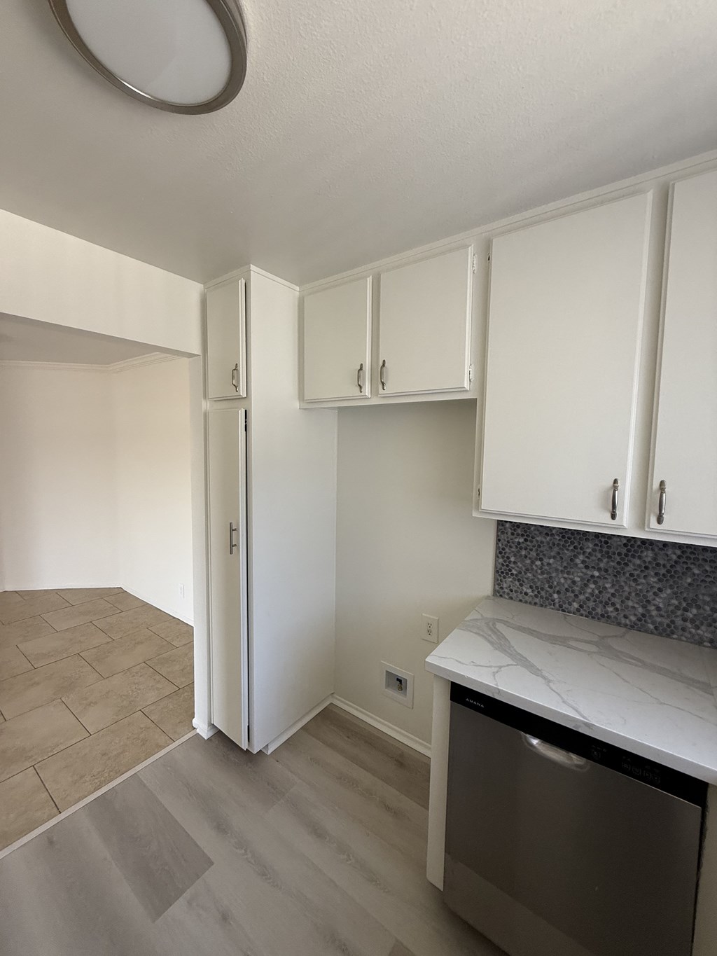 A kitchen with white cabinets and a marble countertop.