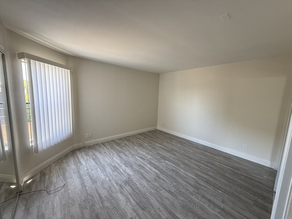 A room with a window and a grey carpet.