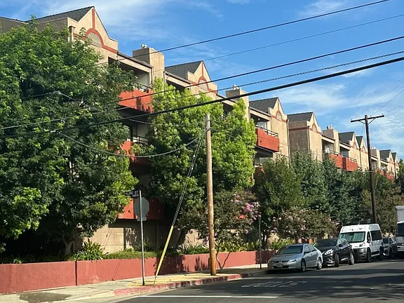 A street view of a residential area with cars parked on the side of the road.