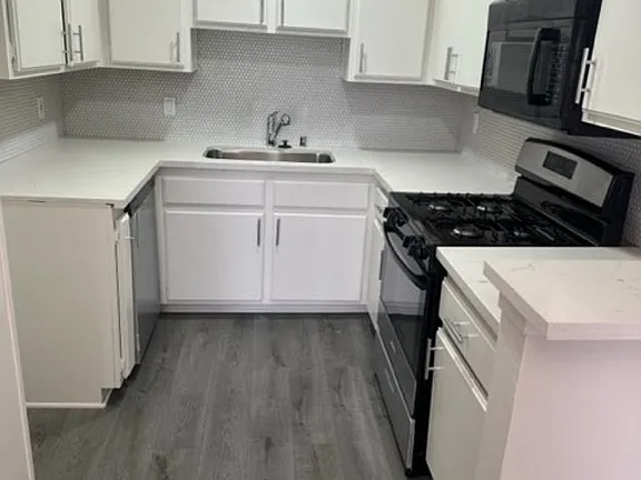 A kitchen with white cabinets and a black stove top oven.