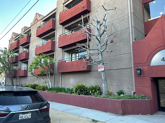 A building with red balconies and a tree in front of it.