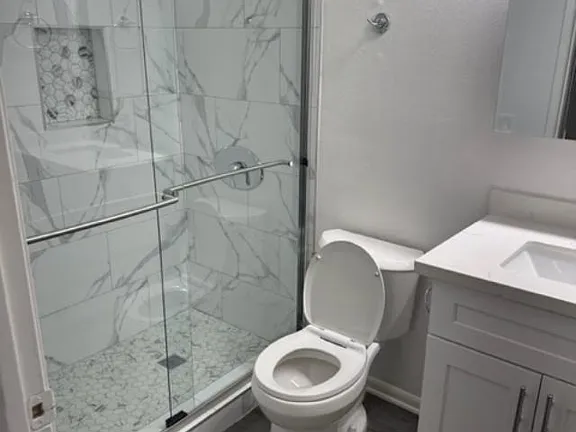 A white toilet in a bathroom with a marble shower.