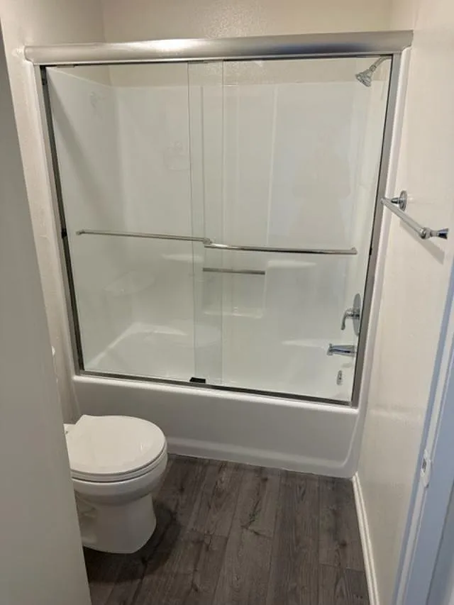 A white toilet sits next to a walk-in shower.