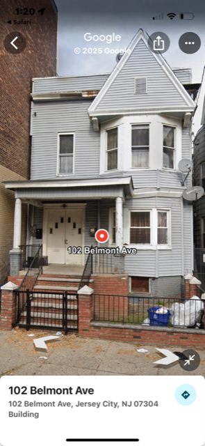 A grey house with a black gate in front of it.
