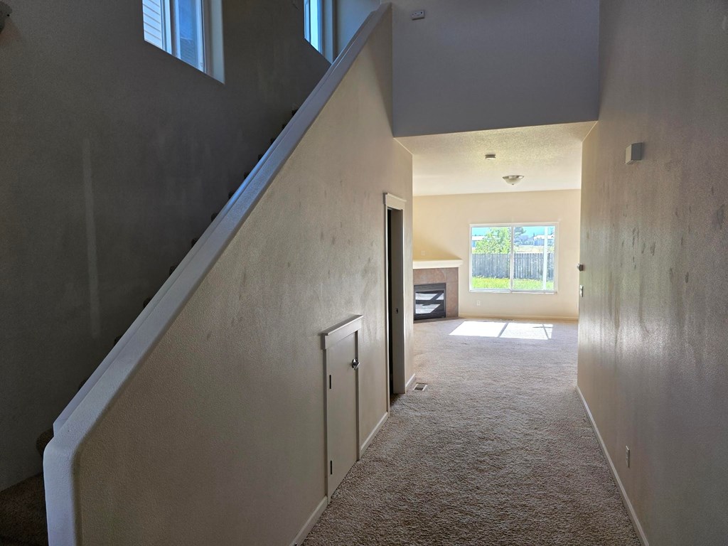 A hallway with a carpeted floor and a door at the end.