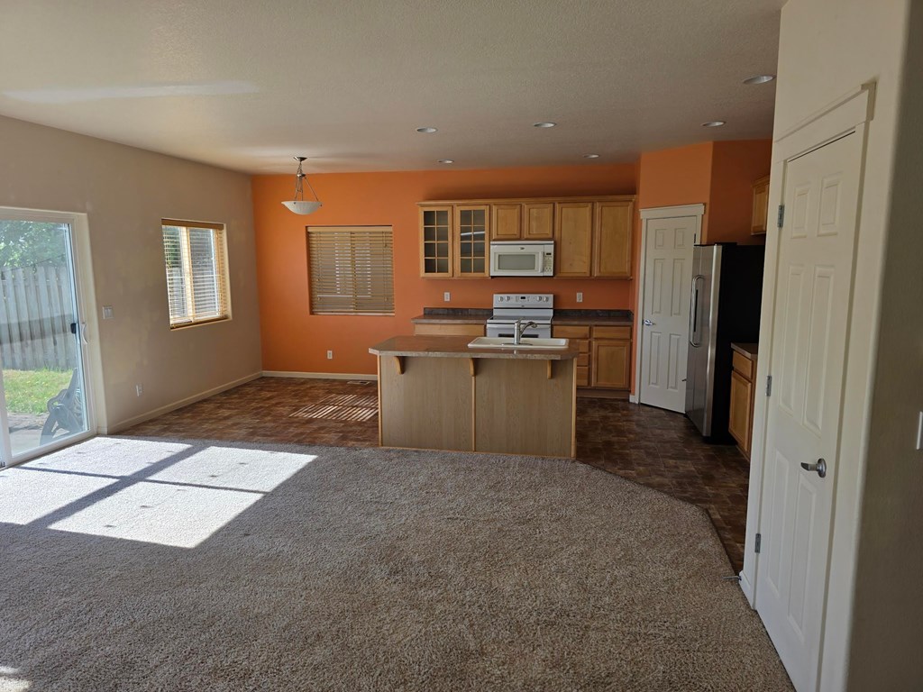 A kitchen with orange walls and white cabinets.
