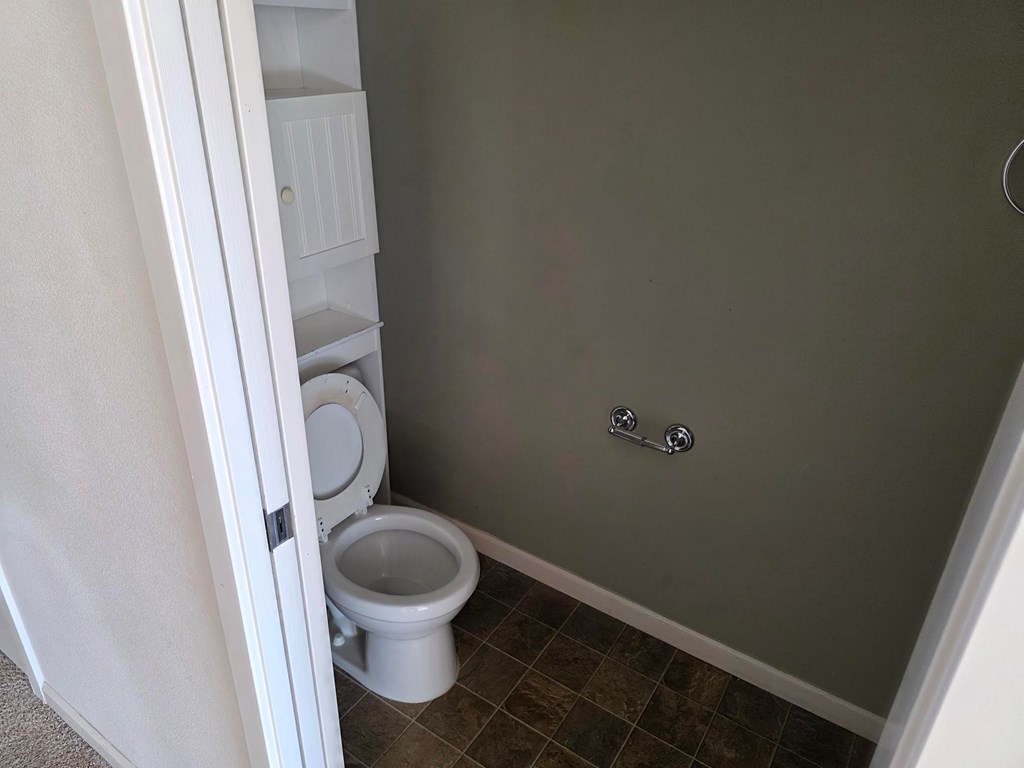 A white toilet is in a small bathroom.