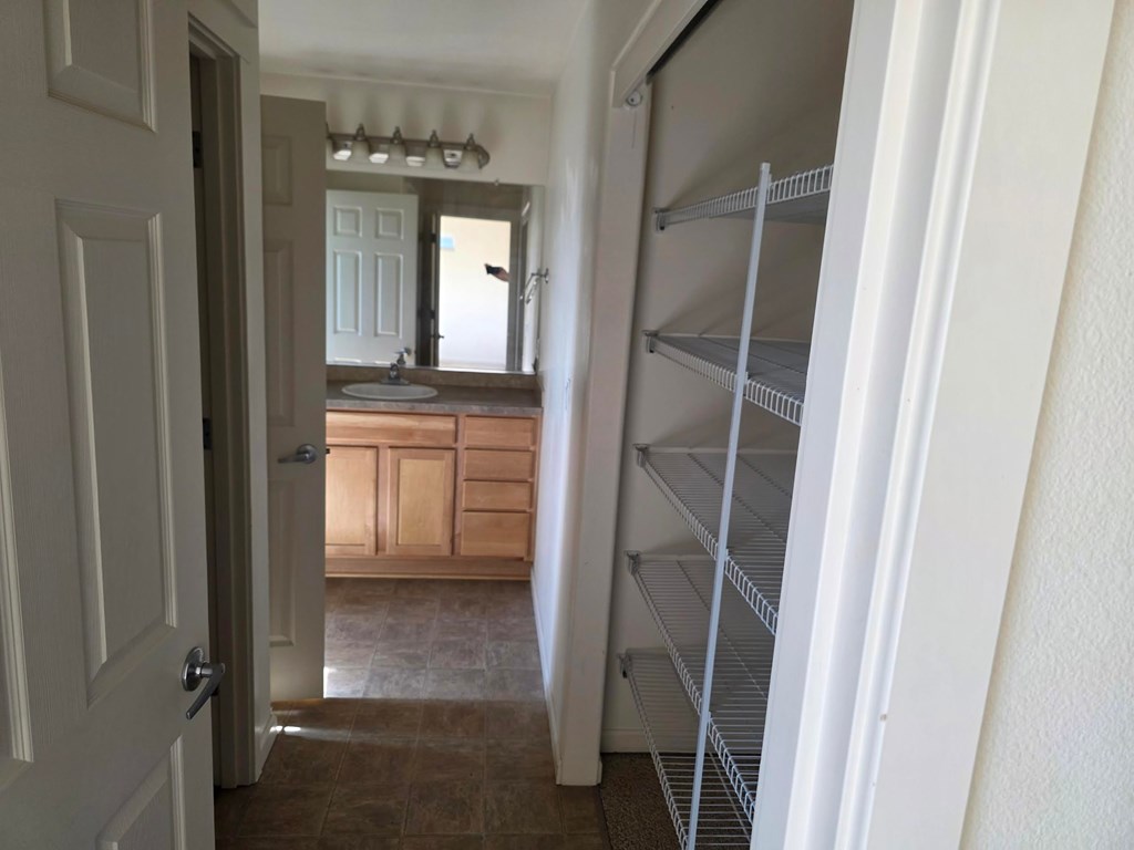 A white door is open to a room with a sink and a mirror.