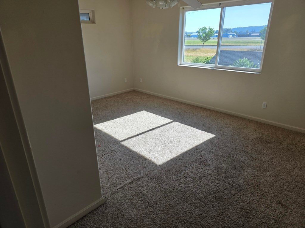 A room with a large window and a carpeted floor.