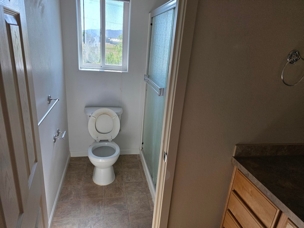 A bathroom with a toilet, a window, and a shower.