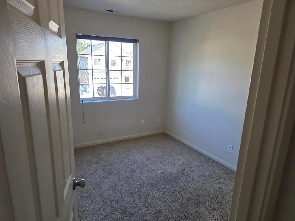A room with a carpeted floor and a window.