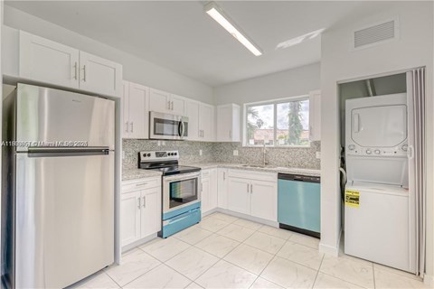 A kitchen with white cabinets and a stainless steel refrigerator.
