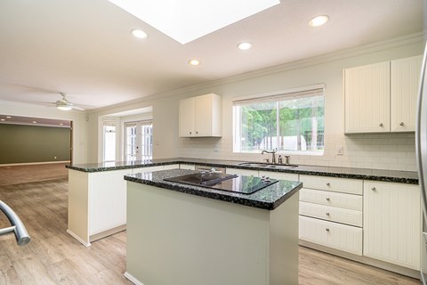 A kitchen with a black granite countertop and white cabinets.