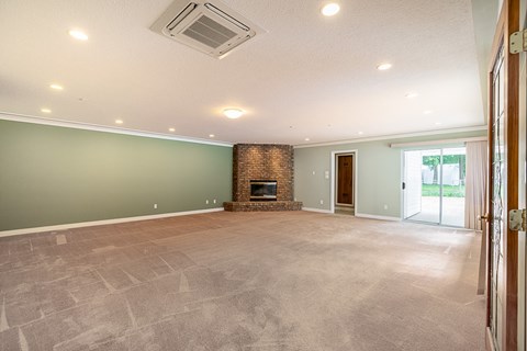 A spacious living room with a fireplace and a sliding glass door.