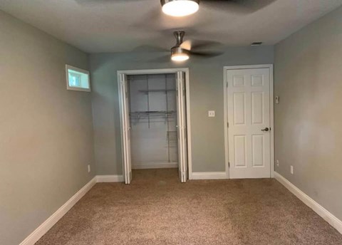 A room with a ceiling fan and a door with a glass panel.