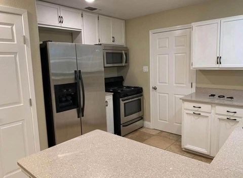 A kitchen with white cabinets and a granite countertop.