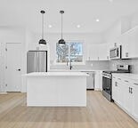 A white kitchen with a wooden floor and white cabinets.