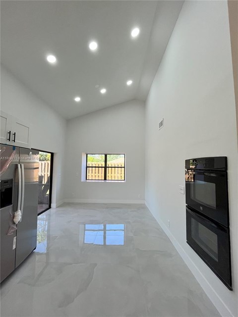 A kitchen with a black oven and a window with blinds.