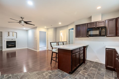 A kitchen with a white countertop and dark wood cabinets.