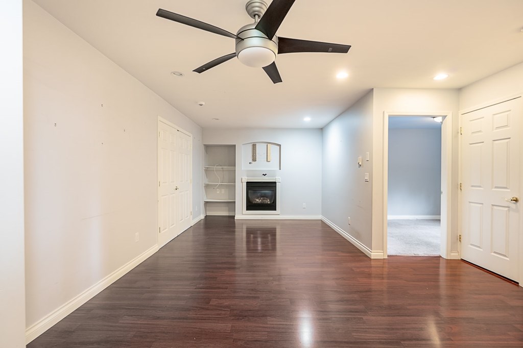 A room with a ceiling fan and wooden floors.