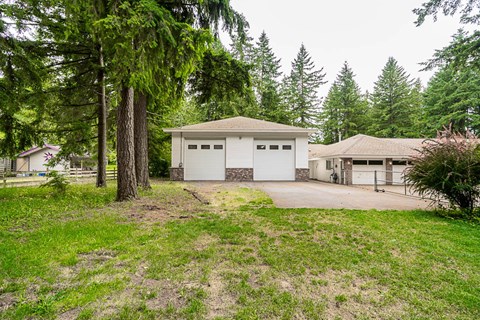 A house with a garage is surrounded by trees.