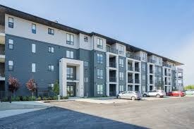 A modern apartment building with a parking lot in front.