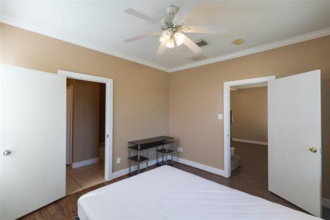A bedroom with a bed, a table, and a ceiling fan.